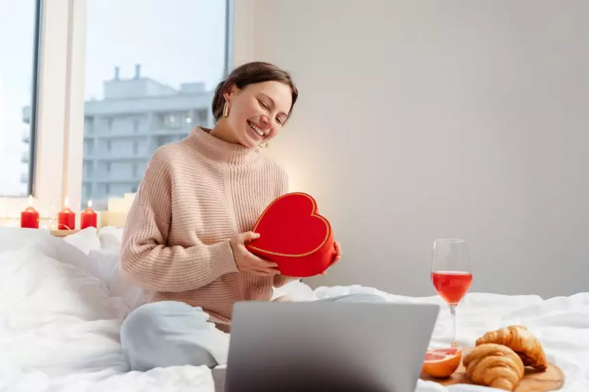 Woman holding gift box using laptop, online dating. Distance relationship, love, Valentine's Day